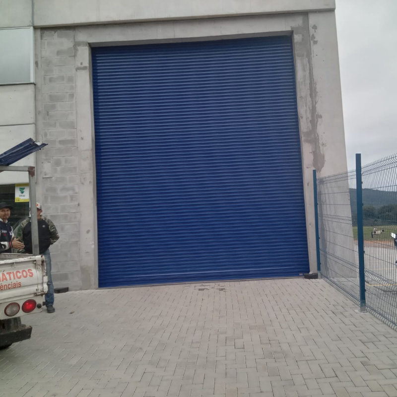 Portão de enrolar azul alto na entrada de um prédio comercial