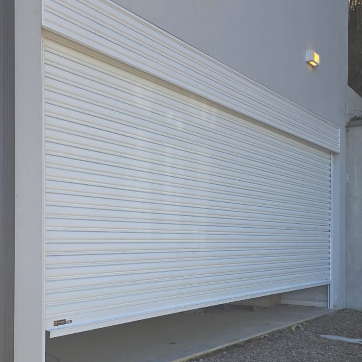 Portão de enrolar branco na garagem de uma casa cinza